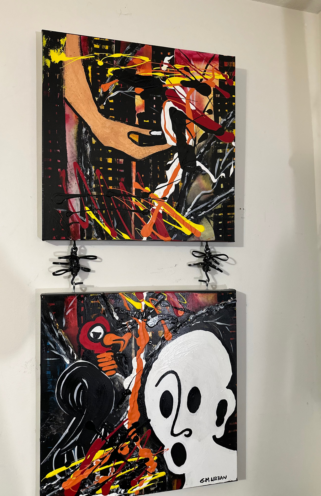 Two abstract artworks hanging on a wall.