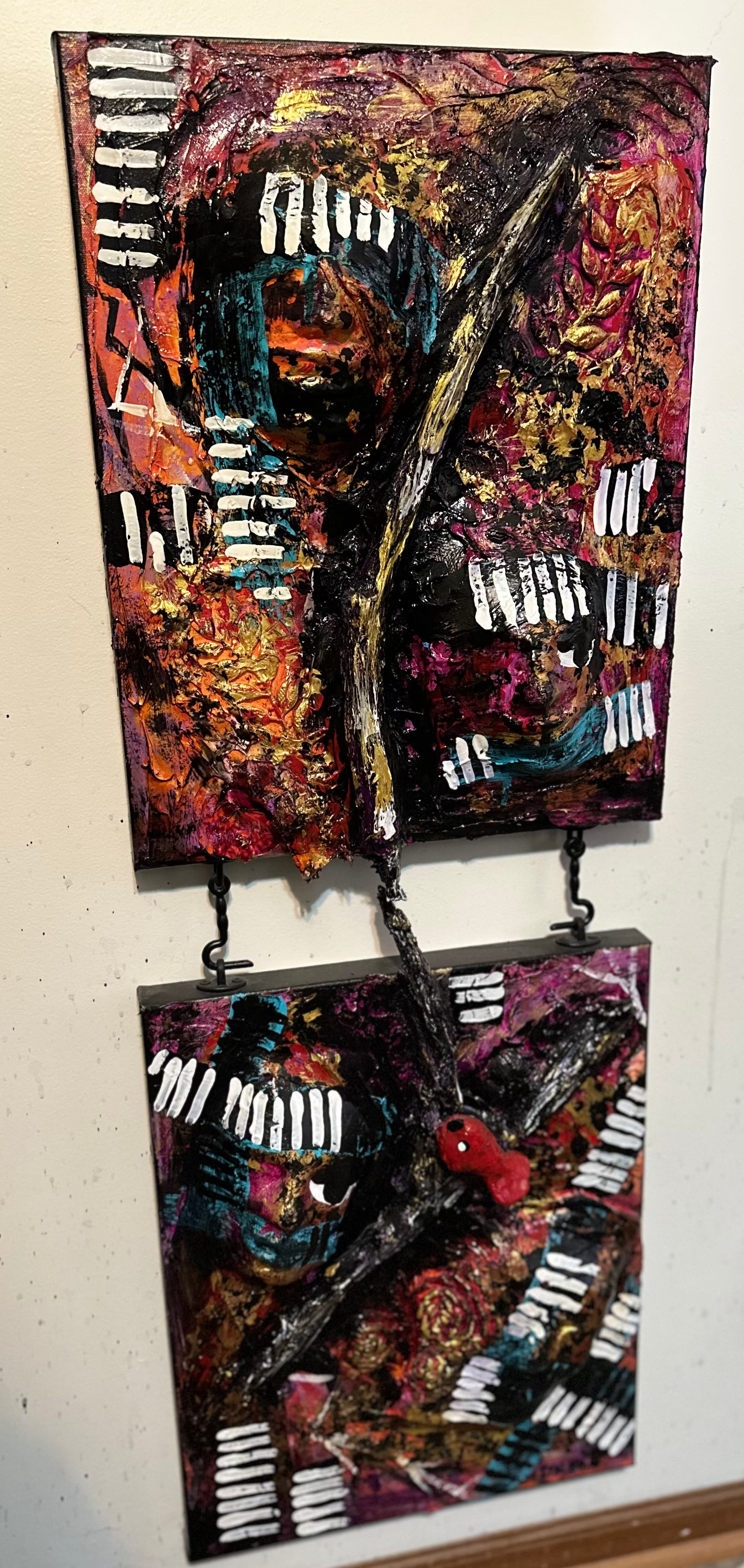 Two abstract art pieces hanging on a wall with a power outlet in the background.